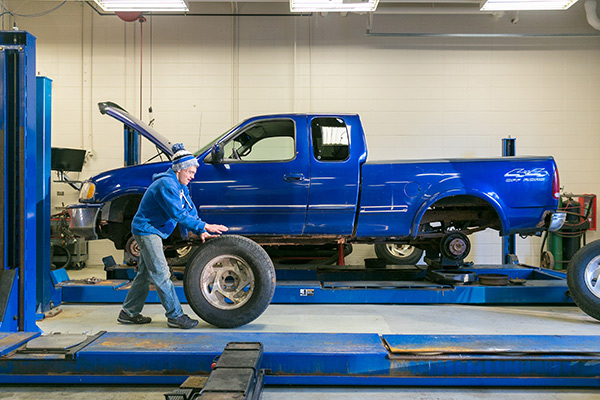 A student puts tires on a truck in the auto lab